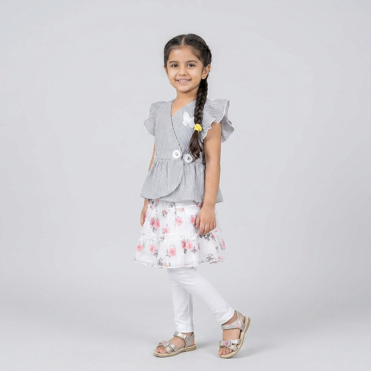 Girl wearing grey pinstripe peplum top with butterfly detail and floral layered skirt elegant party wear outfit for kids