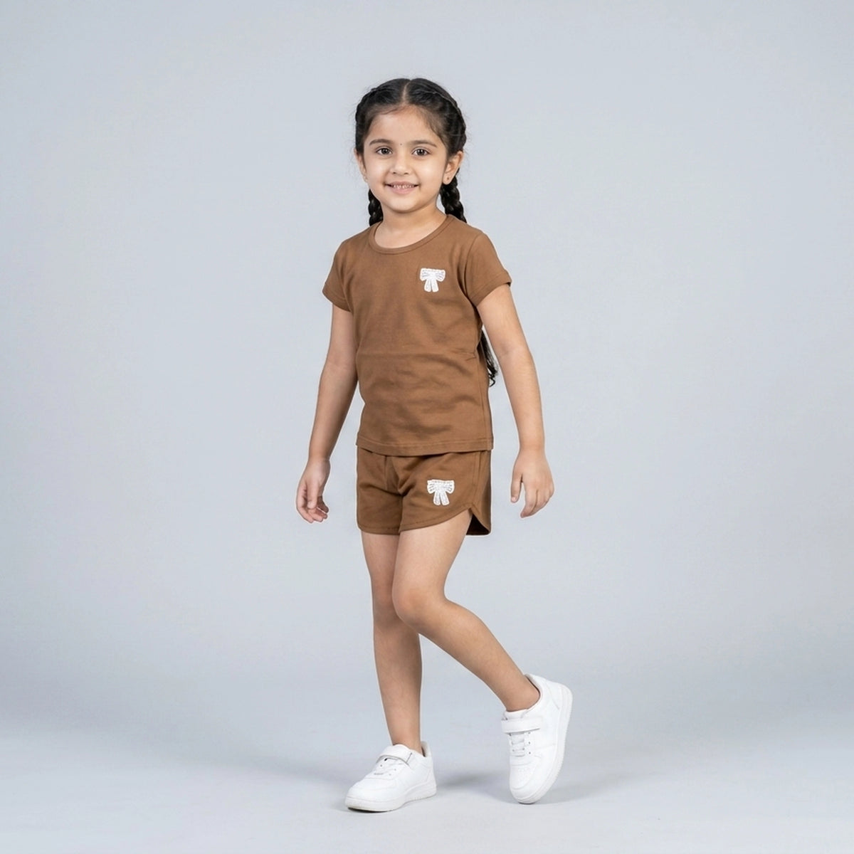 Little girl wearing brown cotton t-shirt and matching shorts co-ord set with bow detail casual summer outfit for kids