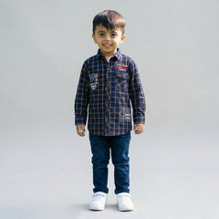 Young boy wearing a Blue checked long-sleeve shirt with dark blue denim jeans and white sneakers against a light studio background