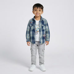 Child wearing a blue plaid shirt, white t-shirt, gray pants, and white sneakers on a light gray background