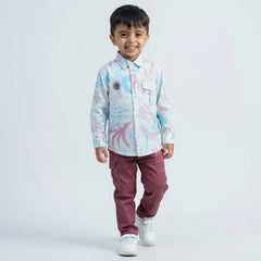 Young boy wearing an abstract print casual shirt with cargo pants and white sneakers, shown in pink color  against a plain light background