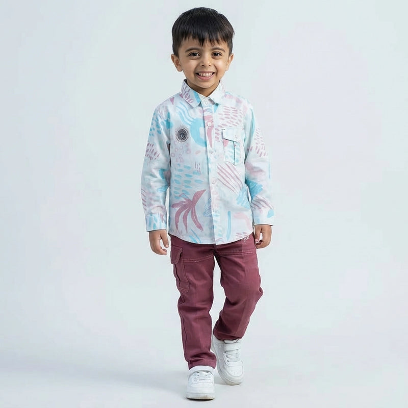 Young boy wearing an abstract print casual shirt with cargo pants and white sneakers, shown in pink color  against a plain light background