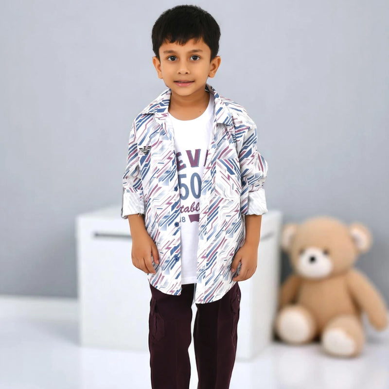Young boy wearing red sunglasses, a white graphic T-shirt, a printed casual shirt, and dark cargo pants, standing indoors with a soft blue background and teddy bear.