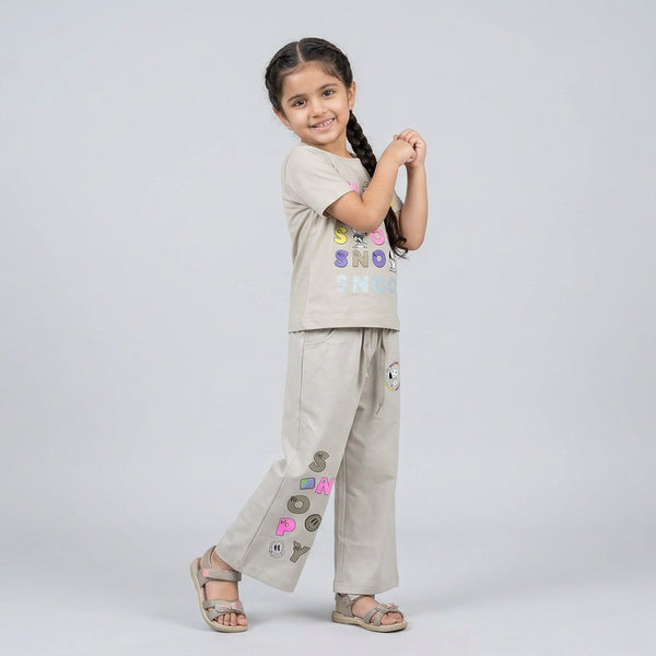 Little girl wearing beige Snoopy printed co-ord set with graphic t-shirt and wide-leg pants for kids casual wear