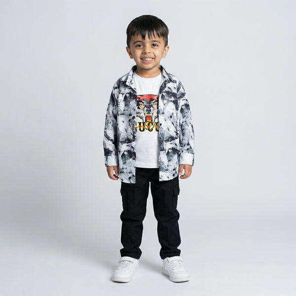 Young boy wearing a black and white printed shirt over a tiger graphic t-shirt with black cargo pants and white sneakers