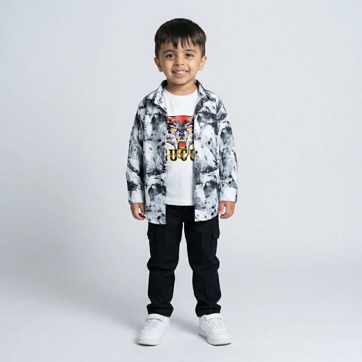 Young boy wearing a black and white printed shirt over a tiger graphic t-shirt with black cargo pants and white sneakers