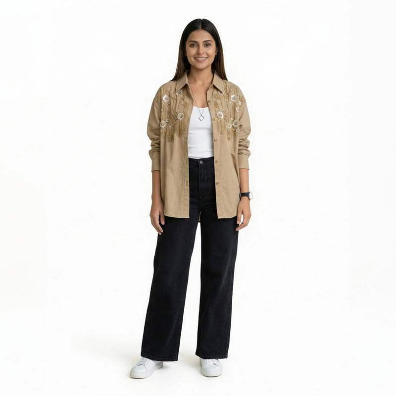 A woman wearing a beige embroidered button-down shirt over a white top, paired with black wide-leg jeans and white