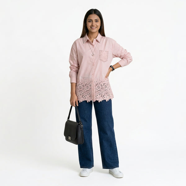Women’s light pink button-down shirt with lace hem detailing, long sleeves, and a relaxed fit, styled with blue wide-leg jeans and white sneakers.