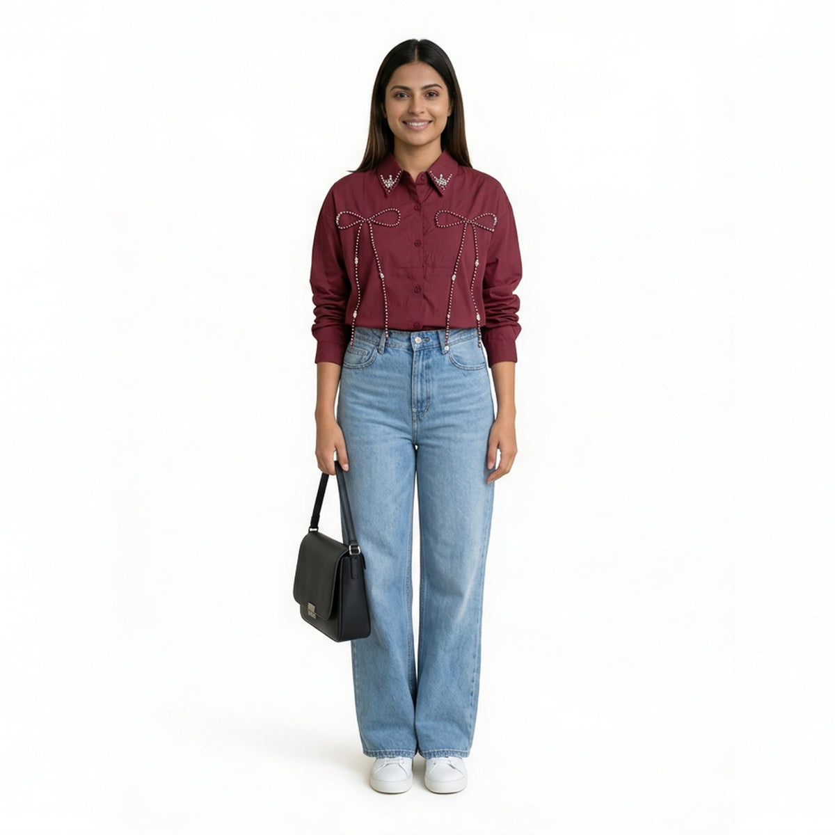 A woman wearing a maroon button-down shirt with bow embellishment details on the front, paired with light blue straight-le