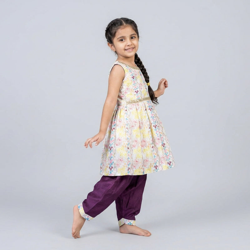 Young girl wearing a floral dress and purple pants on a light gray backgroundgirl w