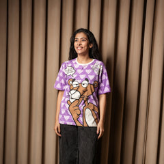 A woman wearing a purple graphic T-shirt with a Pink Panther print, paired with dark jeans, standing against a curtain backdrop.