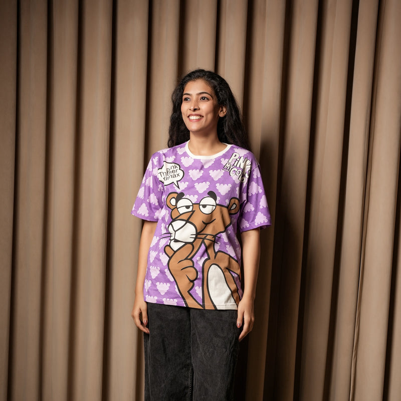 A woman wearing a purple graphic T-shirt with a Pink Panther print, paired with dark jeans, standing against a curtain backdrop.