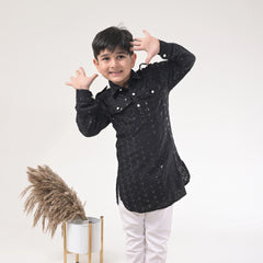 Child wearing a black traditional outfit with white buttons on a white background