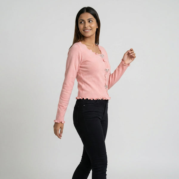 Woman wearing ruffle trim long sleeve top with button detail paired with blue jeans and white sneakers casual outfit