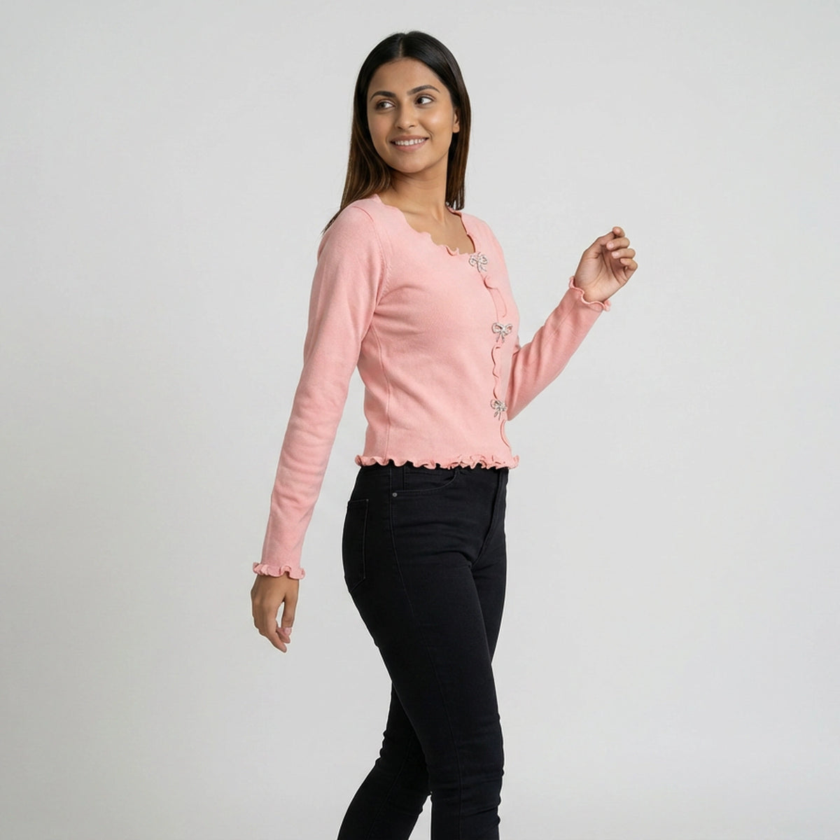 Woman wearing ruffle trim long sleeve top with button detail paired with blue jeans and white sneakers casual outfit