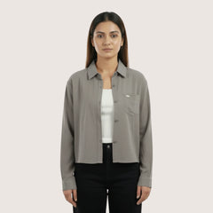 Woman wearing a gray shirt over a white inner on a light beige background