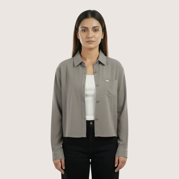 Woman wearing a gray shirt over a white inner on a light beige background