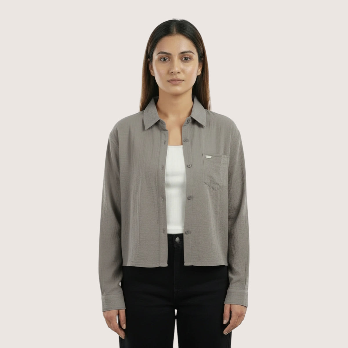 Woman wearing a gray shirt over a white inner on a light beige background